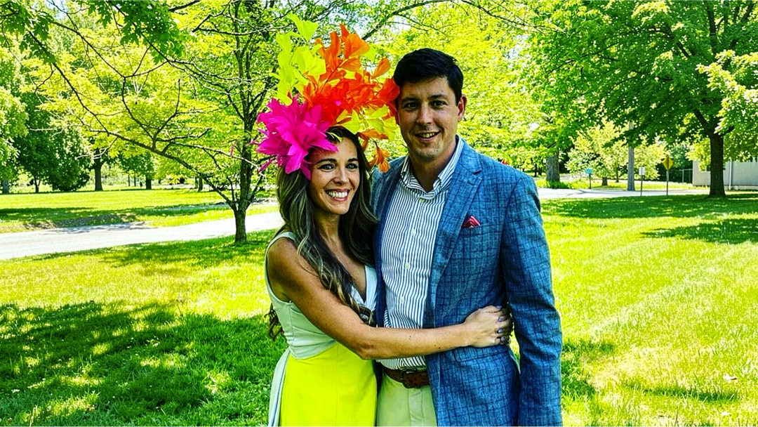 Couple dressed for Derby Day with a colorful fascinator hat at an outdoor horse racing event