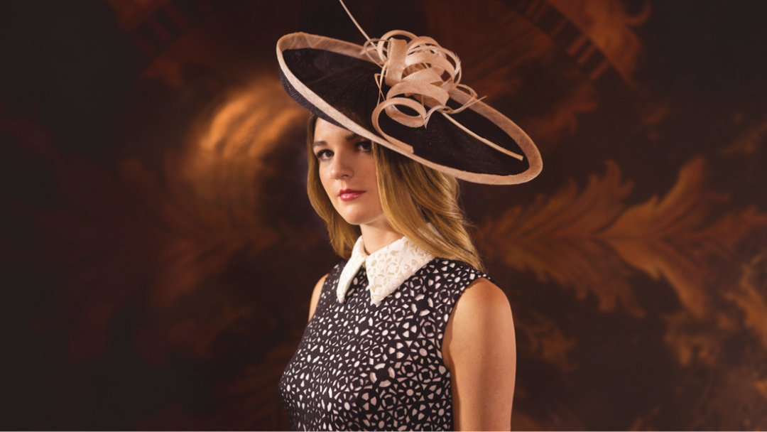 Woman wearing an elegant wide-brimmed fascinator hat with a black and white dress at a formal event