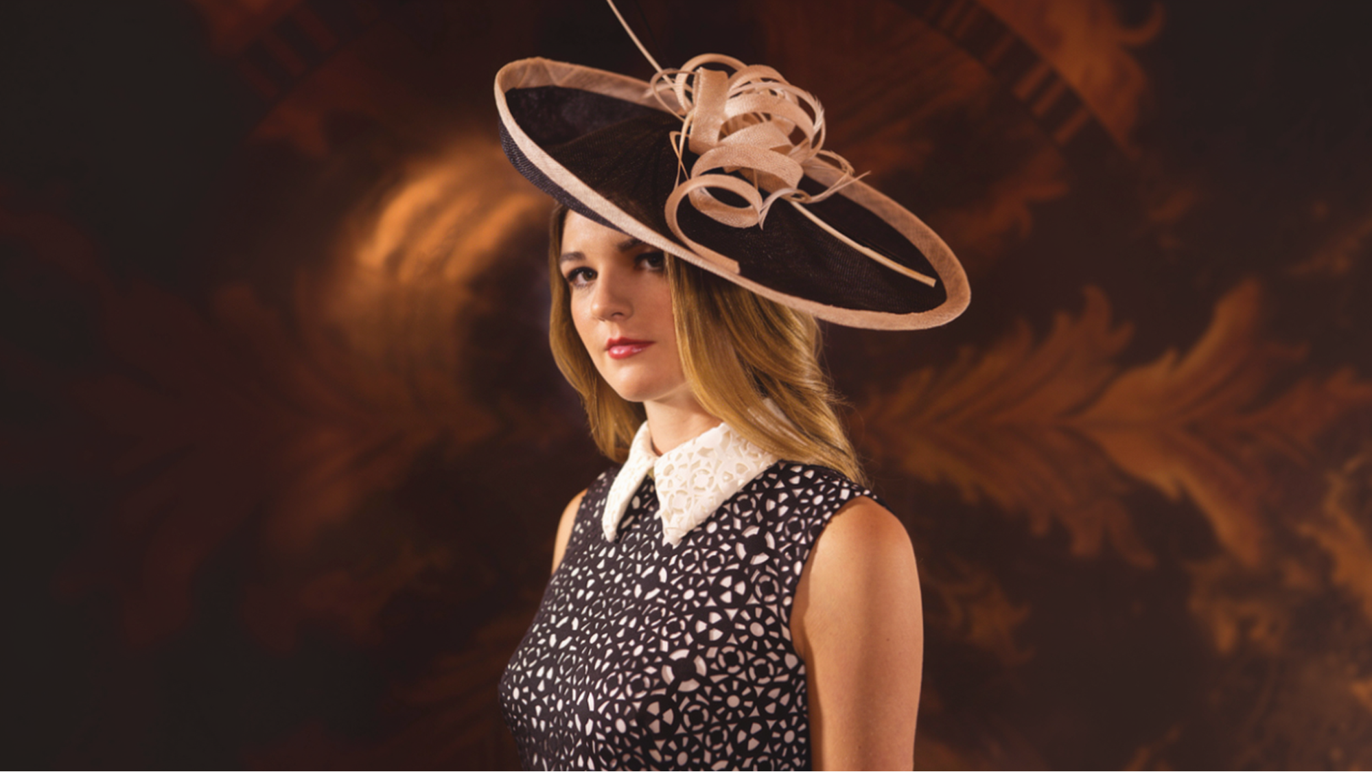 Woman wearing an elegant wide-brimmed fascinator hat with a black and white dress at a formal event